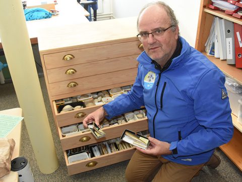 Arthur bij ladenkast vol schelpen